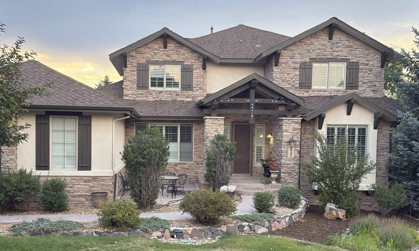 Two-story stone house at dusk with its rooflines traced for measurement